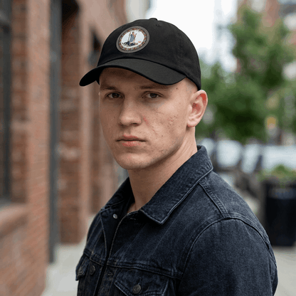 Man wearing a black cap with a tyrant logo outdoors